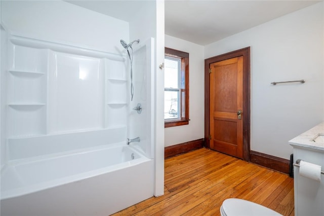 bathroom with shower / bathtub combination, wood finished floors, toilet, and baseboards