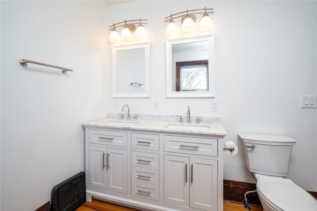 full bath with toilet, double vanity, baseboards, and a sink