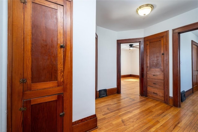 hallway featuring baseboards, visible vents, and light wood-style floors