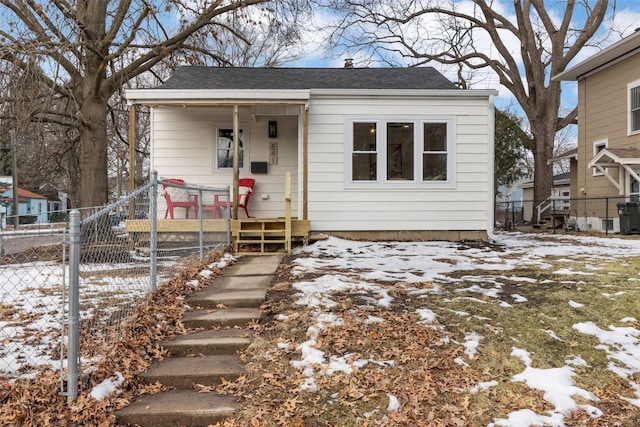 bungalow-style home featuring roof with shingles and fence