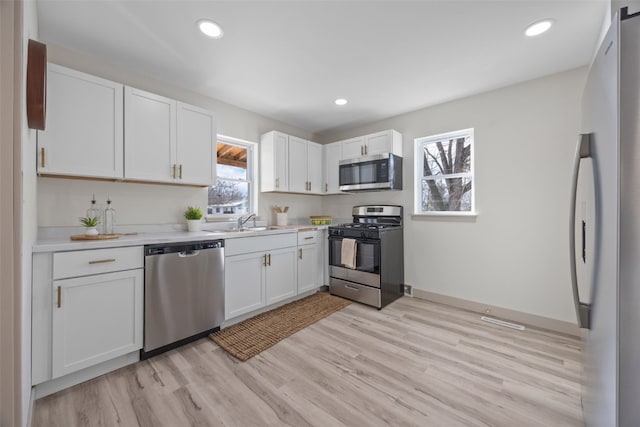 kitchen featuring appliances with stainless steel finishes, white cabinets, light countertops, and plenty of natural light