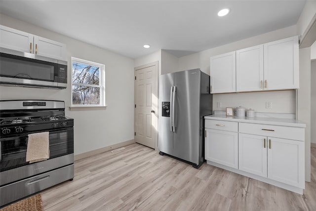 kitchen featuring baseboards, light wood-style flooring, appliances with stainless steel finishes, light countertops, and white cabinetry