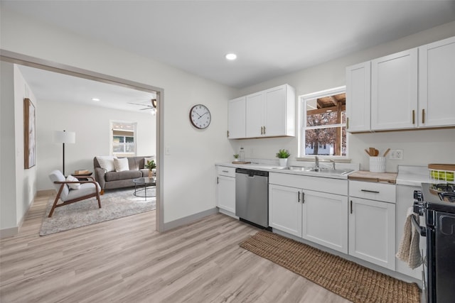 kitchen featuring open floor plan, stainless steel appliances, light countertops, white cabinetry, and a sink