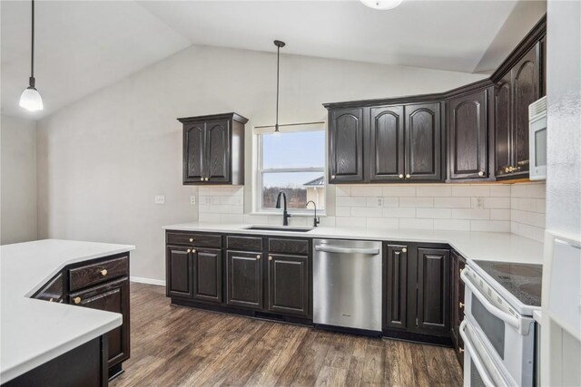 kitchen featuring light countertops, hanging light fixtures, vaulted ceiling, a sink, and white appliances