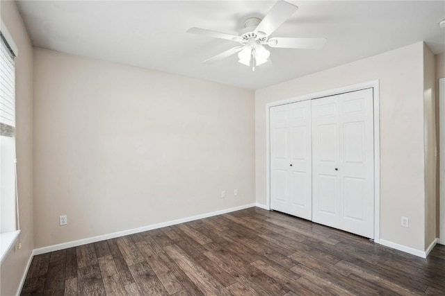 unfurnished bedroom with a closet, dark wood finished floors, and baseboards