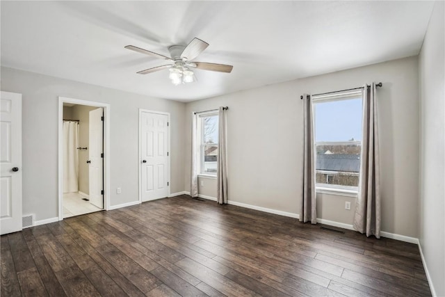 unfurnished bedroom with dark wood-type flooring, connected bathroom, visible vents, and baseboards