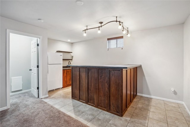 bar featuring track lighting, light tile patterned flooring, freestanding refrigerator, and baseboards