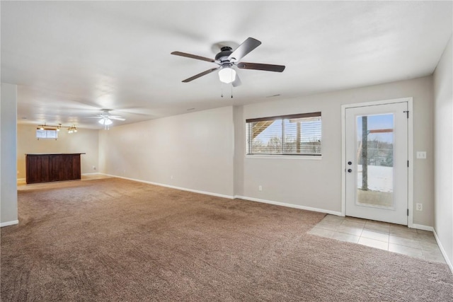 unfurnished living room featuring light carpet, ceiling fan, baseboards, and light tile patterned floors