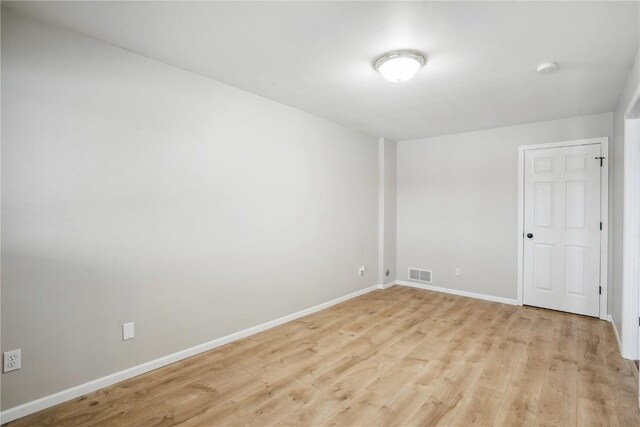 empty room featuring light wood-type flooring, visible vents, and baseboards