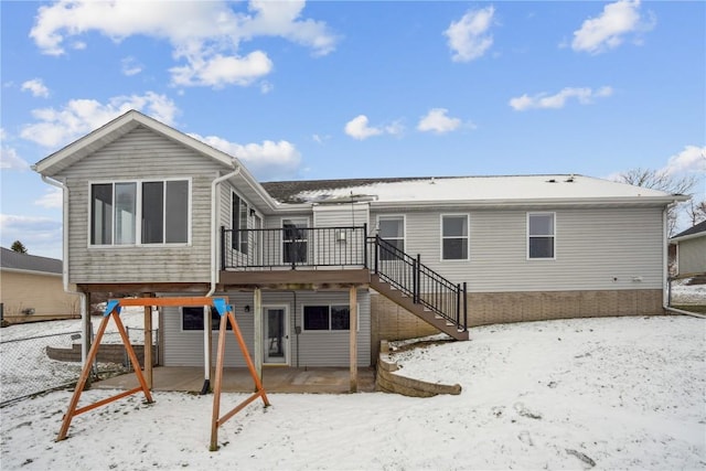 snow covered back of property featuring stairway and a wooden deck