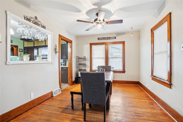 dining space with wood finished floors, visible vents, and baseboards