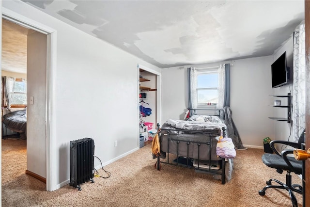 carpeted bedroom with radiator heating unit and baseboards