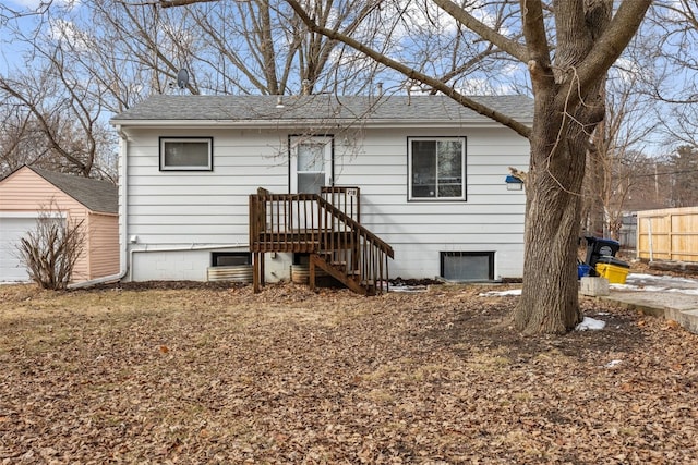 view of front of property featuring a garage, roof with shingles, and fence