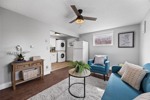 living room featuring dark wood-style floors, a textured ceiling, baseboards, and stacked washer / drying machine