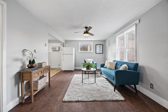 living room featuring dark wood-style flooring, a textured ceiling, and baseboards