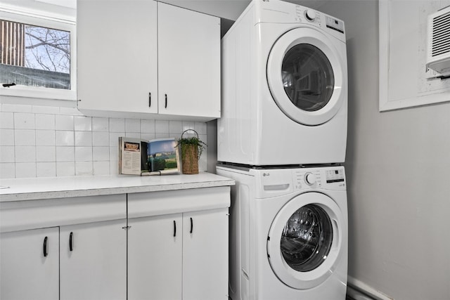 washroom with cabinet space and stacked washer / drying machine