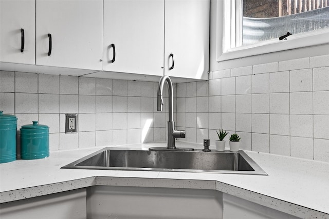 kitchen featuring light countertops, white cabinetry, a sink, and decorative backsplash