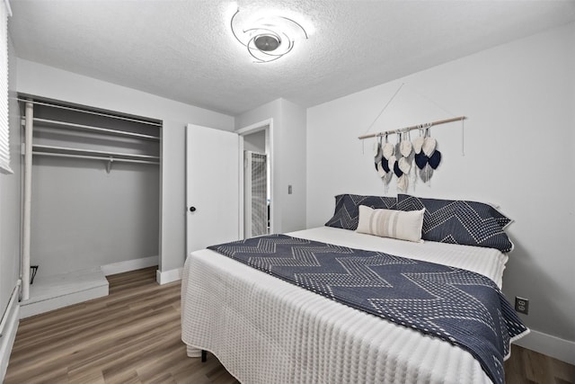 bedroom featuring a textured ceiling, a closet, baseboards, and wood finished floors