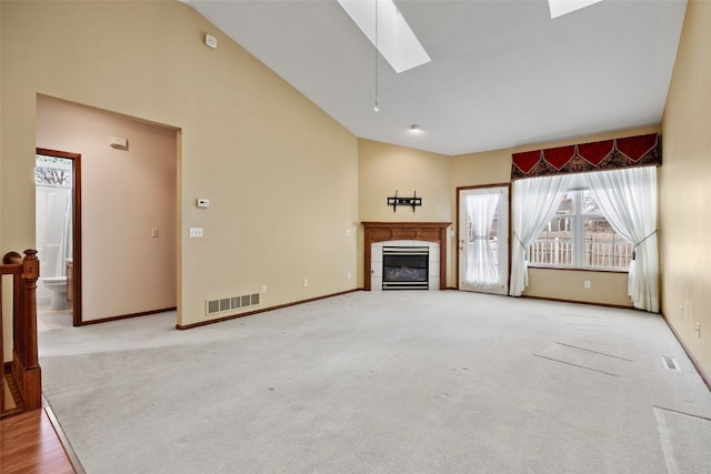 unfurnished living room featuring light carpet, a skylight, a tile fireplace, and visible vents