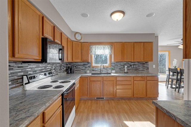 kitchen featuring black microwave, a sink, electric stove, light wood-type flooring, and tasteful backsplash