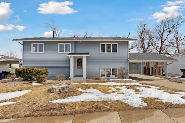 raised ranch with entry steps, an attached carport, and concrete driveway