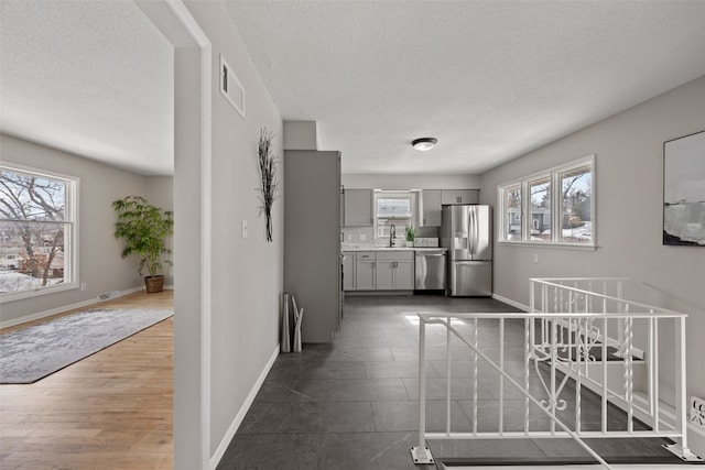 interior space featuring gray cabinetry, visible vents, baseboards, light countertops, and appliances with stainless steel finishes