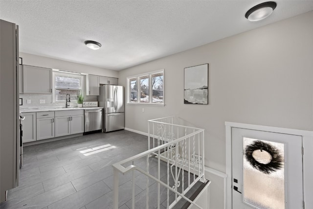 kitchen with a sink, stainless steel appliances, light countertops, and a wealth of natural light