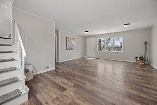 unfurnished living room featuring stairway, a textured ceiling, visible vents, and dark wood-style flooring