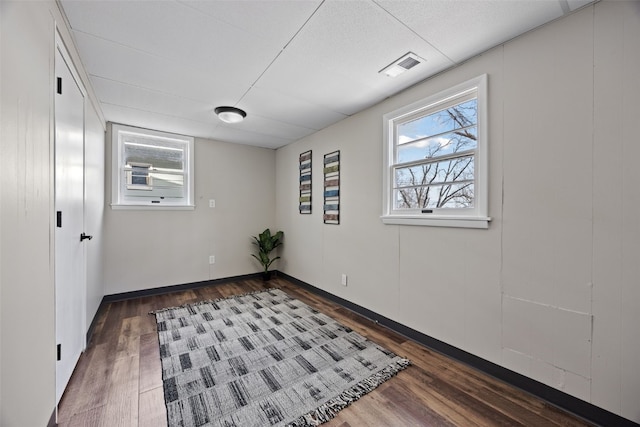 unfurnished room with dark wood-style floors, visible vents, and plenty of natural light