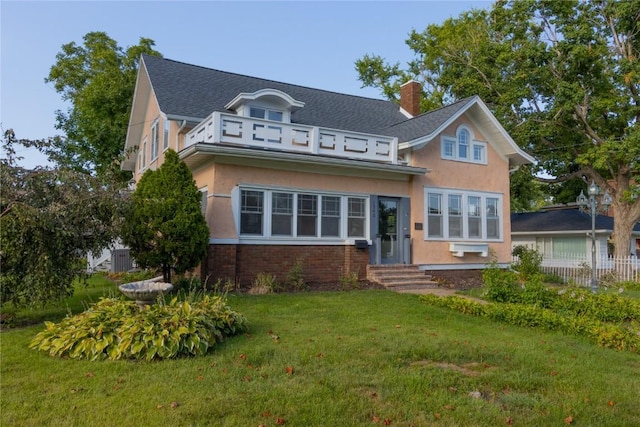 view of front of house with a front lawn, a chimney, brick siding, and stucco siding