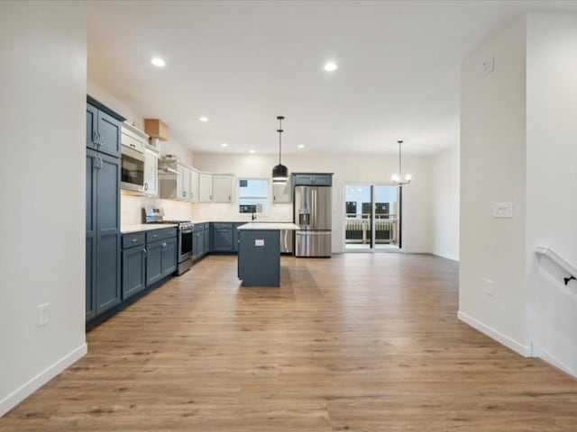 kitchen with pendant lighting, light countertops, appliances with stainless steel finishes, open floor plan, and a kitchen island