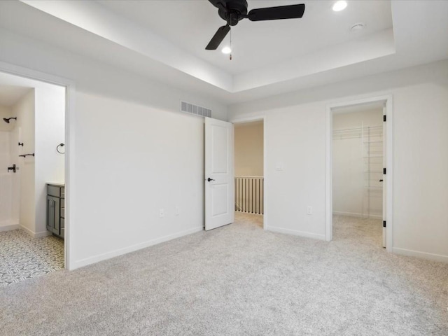 unfurnished bedroom featuring light colored carpet, a raised ceiling, and visible vents