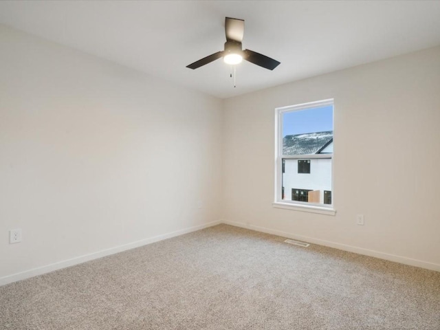 empty room with a ceiling fan, carpet, visible vents, and baseboards