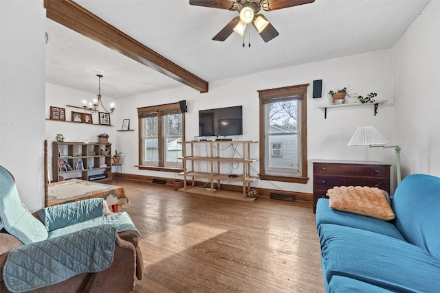 living room featuring ceiling fan with notable chandelier, wood finished floors, beam ceiling, and baseboards