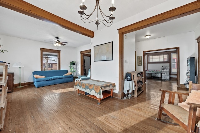 living room with ceiling fan with notable chandelier, a healthy amount of sunlight, beamed ceiling, and wood finished floors