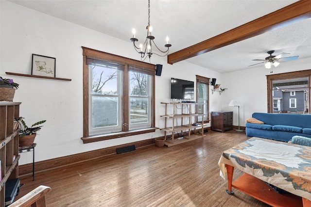 living room featuring ceiling fan with notable chandelier, beamed ceiling, wood finished floors, and baseboards