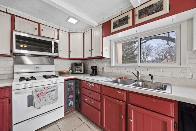 kitchen with white range with gas stovetop, stainless steel microwave, light countertops, and a sink