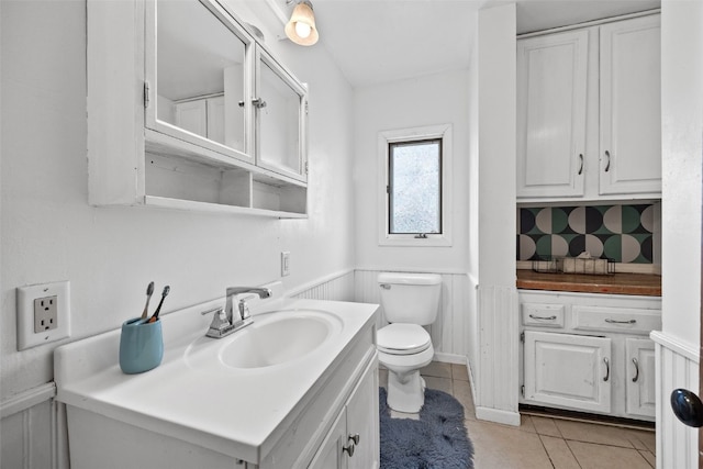 bathroom featuring a wainscoted wall, vanity, toilet, and tile patterned floors