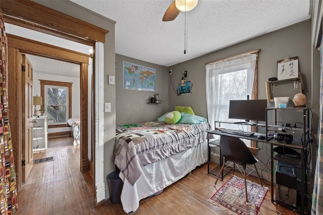 bedroom with hardwood / wood-style flooring, ceiling fan, and a textured ceiling