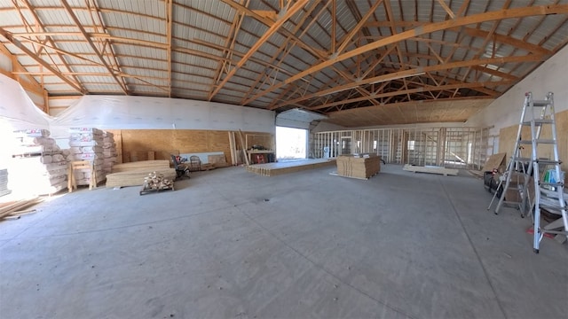 miscellaneous room with high vaulted ceiling, concrete floors, and metal wall