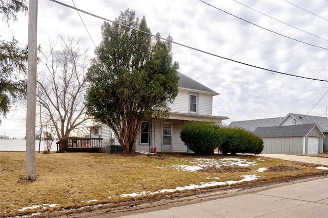 view of front of house with an outbuilding, a wooden deck, and a front lawn