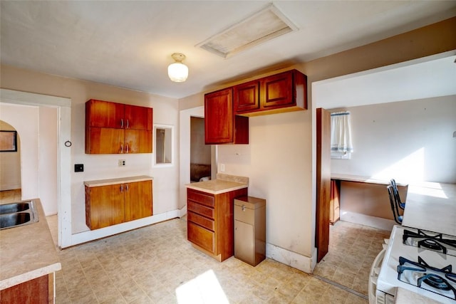 kitchen with light floors, a sink, visible vents, and white range with gas stovetop