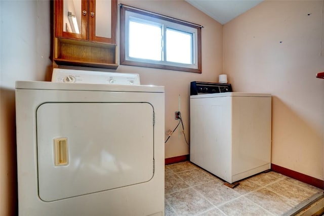 laundry area with washing machine and dryer, laundry area, light tile patterned flooring, and baseboards