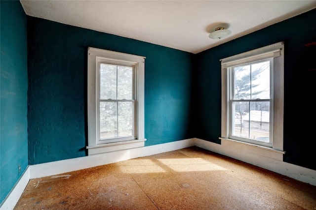 unfurnished room with plenty of natural light and baseboards