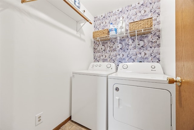 clothes washing area featuring laundry area, wallpapered walls, an accent wall, washer and dryer, and light tile patterned flooring