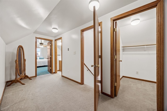 hallway with lofted ceiling, carpet, and baseboards