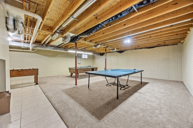 recreation room with brick wall, electric panel, and tile patterned flooring