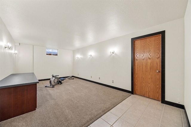 workout area featuring light carpet, baseboards, and light tile patterned floors