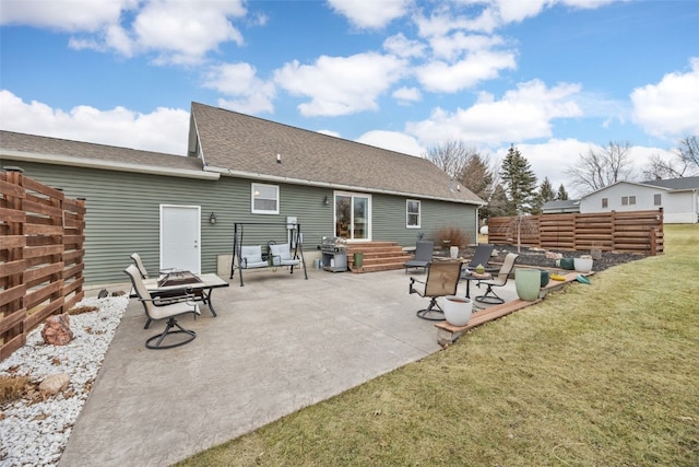 rear view of property featuring an outdoor fire pit, a shingled roof, a lawn, a patio, and fence