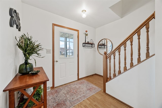 entryway with baseboards, stairway, and light wood finished floors